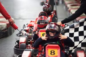Row of children in go-karts with helmets ready for a race